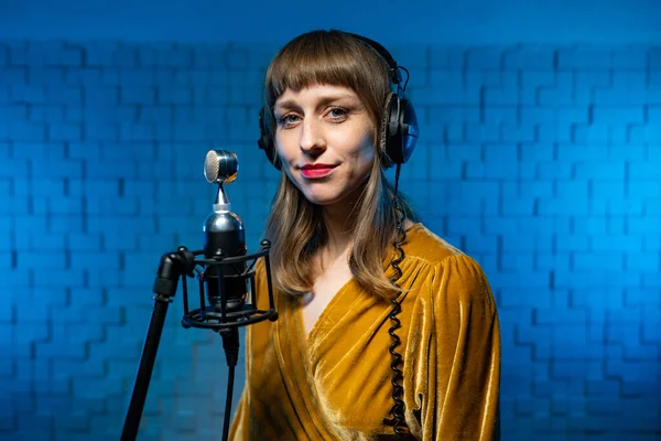 Portrait of a young singer in closed headphones in front of the microphone Stock Photo
