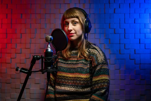 Girl singer in headphones, sweater in recording studio with microphone Royalty Free Stock Photos