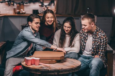 Evde pizzalı gençlik partisi. Arkadaş çemberinde kesik kollu bir adam.