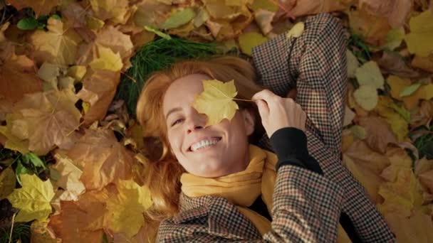 草の上に寝そべってカメラをかじりカエデの葉で目を覆い — ストック動画