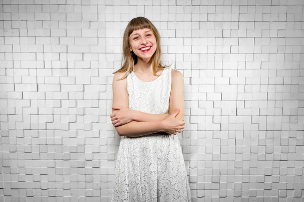 Beyaz elbiseli neşeli kız kameraya bakar, mutlu bir şekilde gülümser.