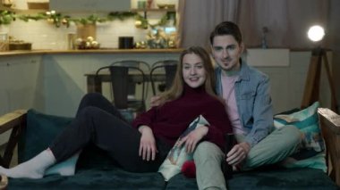 Genç bir çift kanepede oturup film seyrediyor.