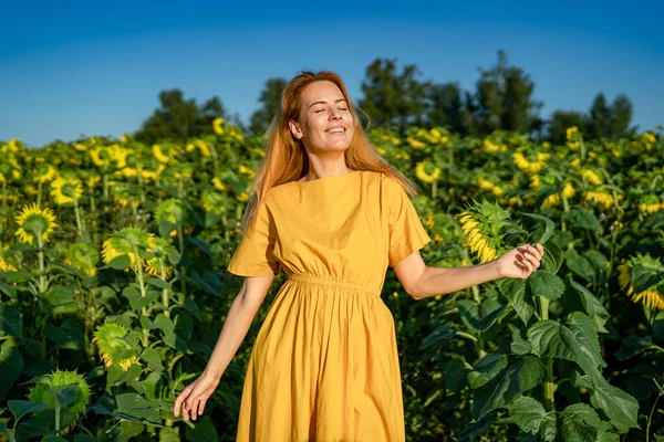 Woman enjoys sunny weather, dancing with closed eyes in sunflower field Royalty Free Stock Photos