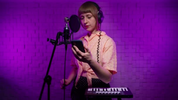 Девушка певица записывает песню в студии с микрофоном с поп-фильтром, смартфоном — стоковое видео
