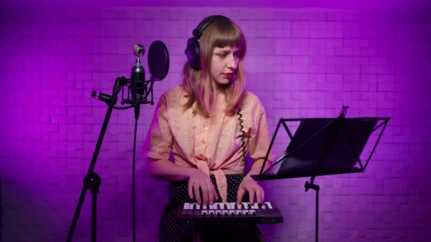 Girl in headphones learns to play drum pad in recording studio with music stand — Vídeo de Stock