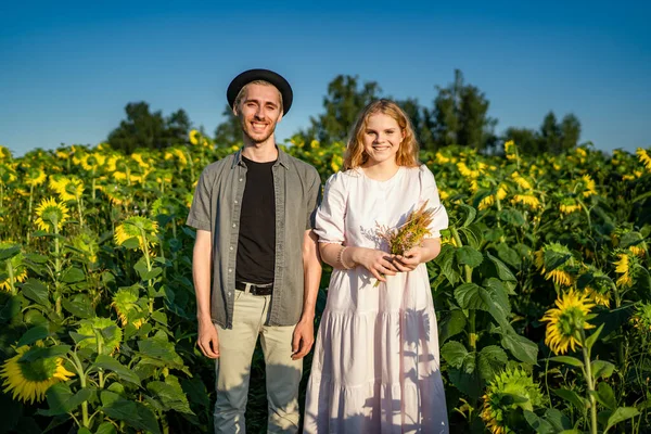 A happy young couple poses for a camera in a sunflower field Stock Image