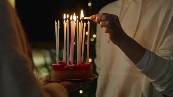 Close-up. As mãos acendem velas no bolo de aniversário. Velas altas multicoloridas — Vídeo de Stock