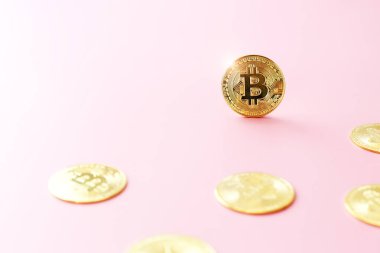 Açık pembe arka planda altın Bitcoin 'i kapat. Kripto para birimi sembolü. Parlak bitcoin altın madeni paralar arasında yer alır..