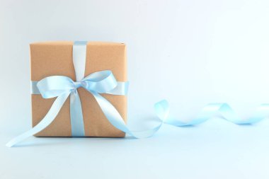 Pastel mavi arka planda mavi saten kıvrımlı kurdeleli güzel kahverengi kağıt hediye kutusunu kapat. Anneler günü, babalar günü, sevgililer günü, fotokopi çekilen doğum günü kavramları..