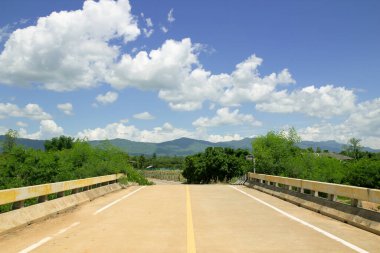Güzel yeşil doğanın ve mavi gökyüzünün önüne uzanan beton köprü.