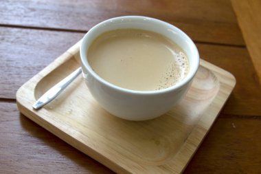 Tahta arka planda beyaz bir fincanda bir fincan kahve.