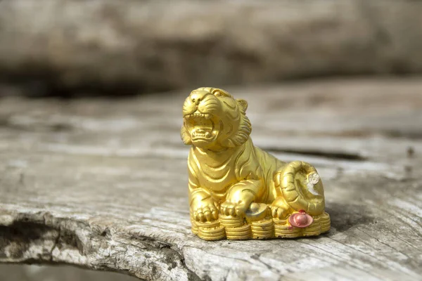 Golden tiger statue placed on an old wooden floor
