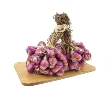 Tahta kesme tahtasındaki arpacık soğanları beyaz arka planda izole edilmiş.