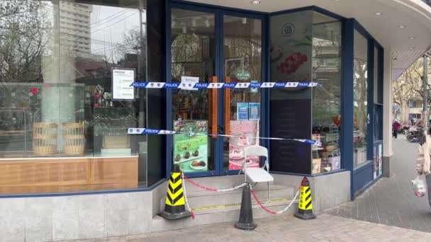 ШАНХАЙ, КИТАЙ - 31 марта 2022 года: женщина проходит мимо магазина, закрытого полицейской лентой — стоковое видео
