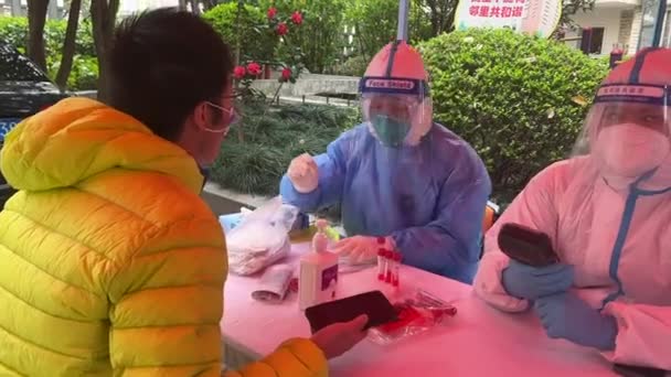 SHANGHAI, CHINA - April 3, 2022: two people in hazmat suits do covid test on man — Stock Video