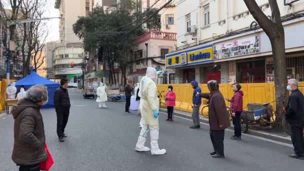 ШАНХАЙ, КИТАЙ - 4 апреля 2022 года: защитные костюмы регистрируют людей для тестирования на ковид — стоковое видео