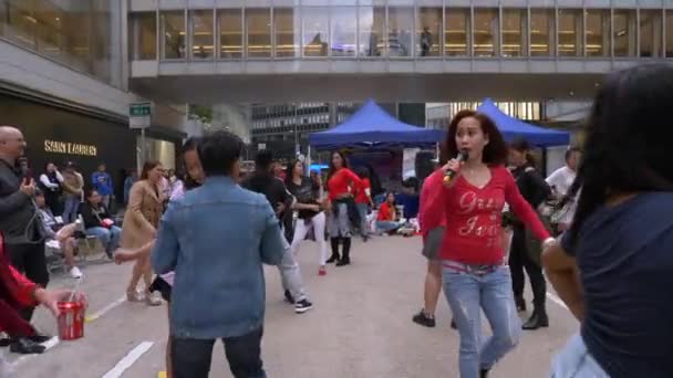 HONG KONG - 23 JANUARI 2020: Instruktör som samordnar dansande människor för en flashmob på gatan i Kina — Stockvideo