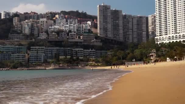 Bela praia de areia junto ao mar e a grande cidade de Hong Kong ao fundo em sol Filmagem De Bancos De Imagens Sem Royalties