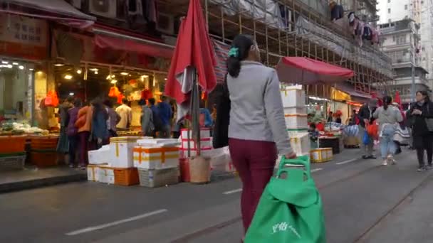 HONG KONG - 21 de enero de 2020: La mujer pasa por las tiendas y el mercado de alimentos en una calle concurrida en el centro de la ciudad Clip De Vídeo