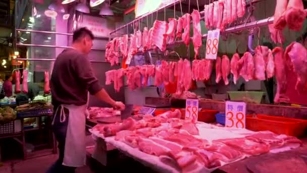 HONG KONG - JANUARI 21, 2020: Jongeman snijdt vlees bij de slagerij op de voedselmarkt in Hongkong, China Rechtenvrije Stockvideo's