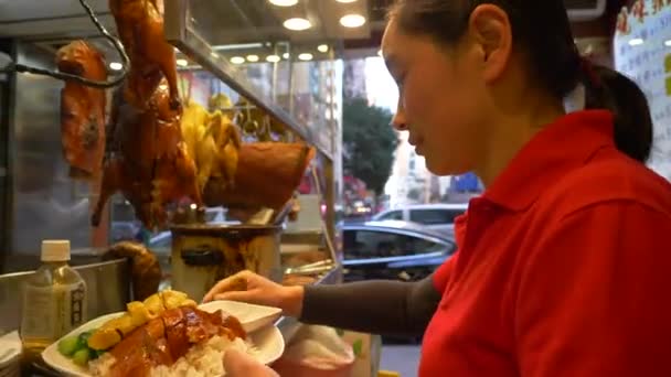 HONG KONG - JANEIRO 21, 2020: Mulher com uma camiseta vermelha recebe comida no balcão de carne no mercado de alimentos em Hong Kong, China — Vídeo de Stock