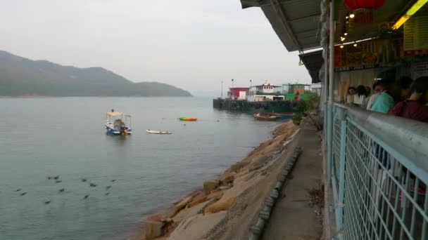 Een kleine boot drijft op het water tegen de achtergrond van gebouwen in Hong Kong overdag vanuit een uitzicht op het gebouw Stockvideo's