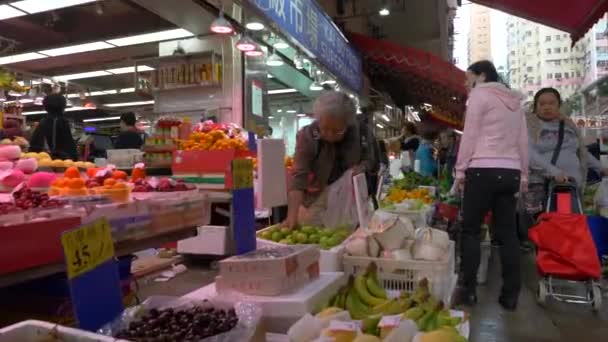 HONG KONG - JANUARI 21, 2020: Mensen kopen groenten en fruit op een voedselmarkt in China Stockvideo