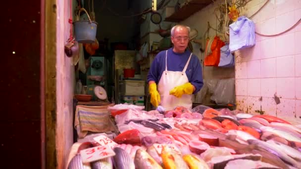 HONG KONG - 21. ČERVENCE: Starý rybář prodává čerstvé ryby na místním trhu s potravinami a stará žena nakupuje ryby. — Stock video