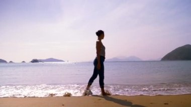 Güzel melez genç bir kadın gün ışığında Hong Kong sahilinde yürüyor.