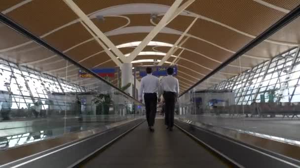 Homens de terno na calçada móvel vazia devido ao coronavírus no aeroporto de Hong Kong — Vídeo de Stock