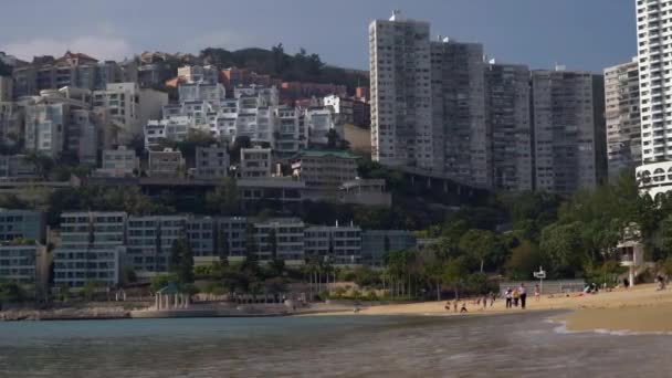 Bela praia arenosa de Hong Kong junto ao mar e a grande cidade ao fundo em sol — Vídeo de Stock