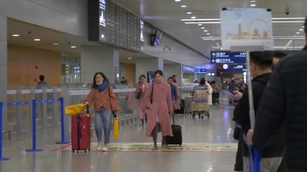 HONG KONG - STYCZEŃ 23, 2020: Osoby z bagażem przejeżdżające przez terminal przylotów na lotnisku — Wideo stockowe