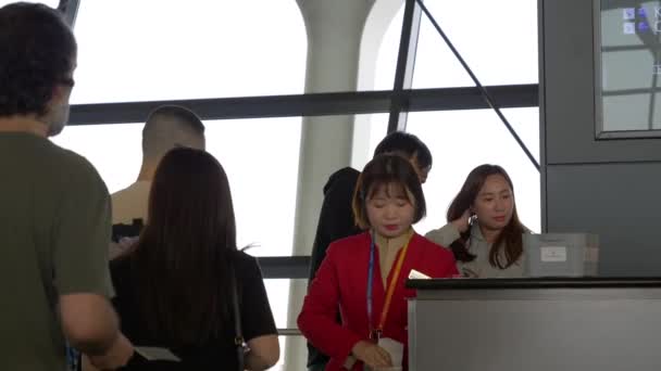 HONG KONG - JANEIRO 20, 2020: As trabalhadoras verificam os viajantes com bagagem no portão antes de embarcar em um avião no aeroporto de Hong Kong — Vídeo de Stock