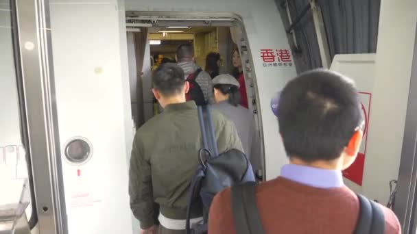 HONG KONG - JANUARI 20, 2020: Passagiers klaar om op een vliegtuig te stappen en stewardessen begroeten reizigers — Stockvideo