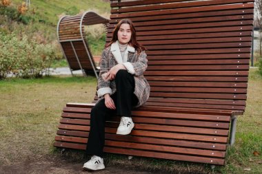 Düşünceli, düşünceli, paltolu genç bir kadın tek başına dikiliyor ve başka tarafa bakıyor. Üzgün kadın hayal kuruyor, sonbahar parkında düşünüyor. Sonbahar bunalımı, moralim bozuk. Birini bekliyorum. Sıradan bir şehir kıyafeti. Yaşam biçimi