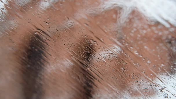 Des gouttes de neige et de pluie tombent sur une fenêtre en verre. Il pleut sur la neige. Concentration sélective — Video