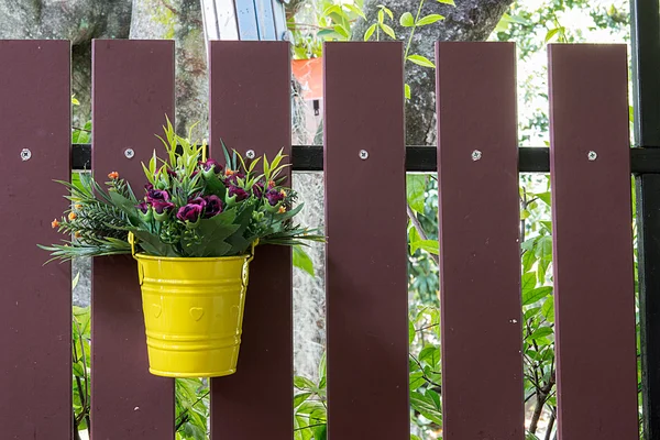 Cubo de flores sobre una cerca —  Fotos de Stock