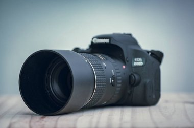 Galle, Sri Lanka - 02 18 2021: Canon DSLR kamera ve 100 mm makro lens ile ahşap masa üzerinde lens kaputu görüntüsü.