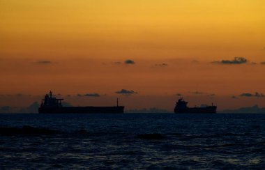 Ufukta boş kargo gemileri, gökyüzünde puslu pastel günbatımı renkleri ve siluetli gemiler. Galle, Sri Lanka 'daki sahilin yakınındaki manzara fotoğrafı..