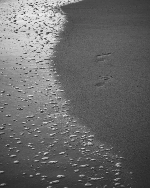 海の泡とビーチの足跡黒と白の写真 — ストック写真
