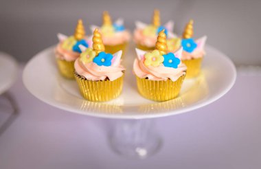 Tek boynuzlu at temalı 6 güzel kek kürsüde, doğum günü partisi tatlıları kapanıyor. Buzlu tek boynuzlu at boynuzu ve keklerin üstünde çiçekler..