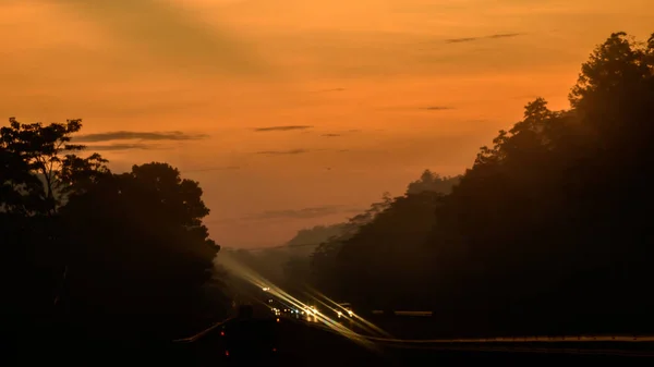 Orangefarbener Himmel Und Die Silhouettierten Bäume Morgen Der Schnellstraße Fahrzeugscheinwerfer — Stockfoto