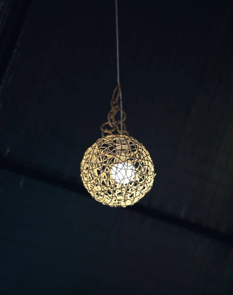 A glowing round light bulb against the dark ceiling.