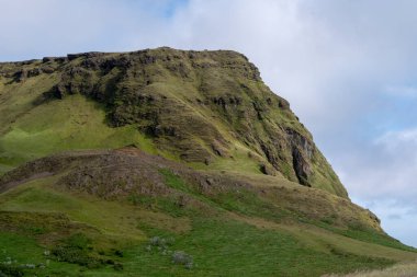 Vik 'teki çimenli uçurumların bulutlu manzarası