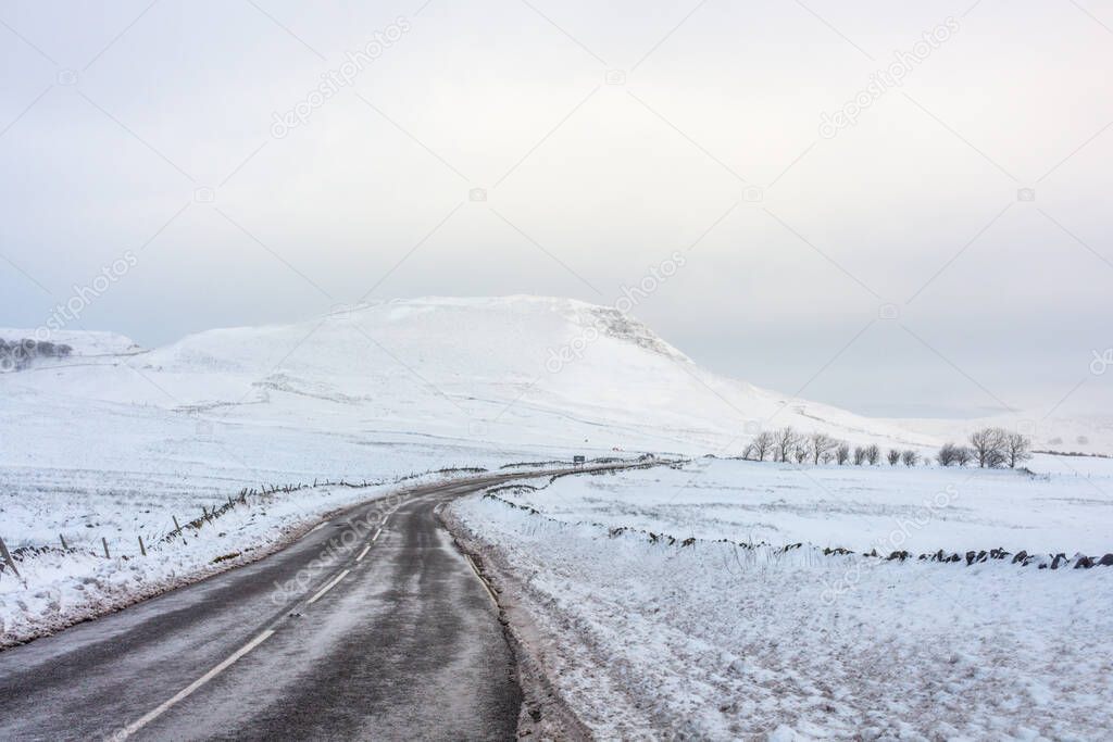 Winter view of road through snow covered countryside. Perak District, Derbyshire, UK.