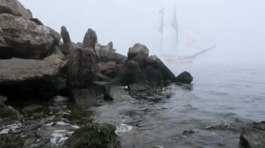 zeilboot in volledige zeil komt uit mist