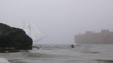 zeilboot in volledige zeil komt uit mist