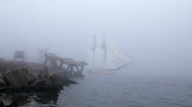 zeilboot in volledige zeil komt uit mist