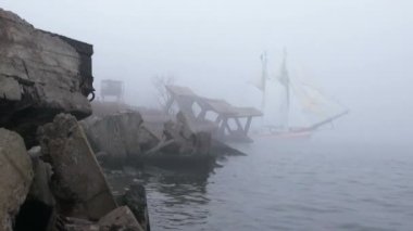 zeilboot in volledige zeil komt uit mist