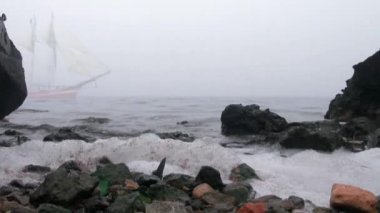zeilboot in volledige zeil komt uit mist